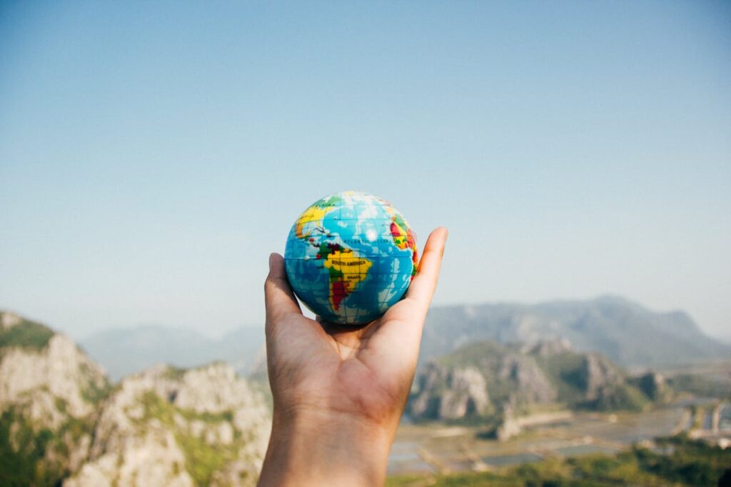 pexels-photo-346885 Hand holding a globe against a mountain background symbolizing travel and exploration.